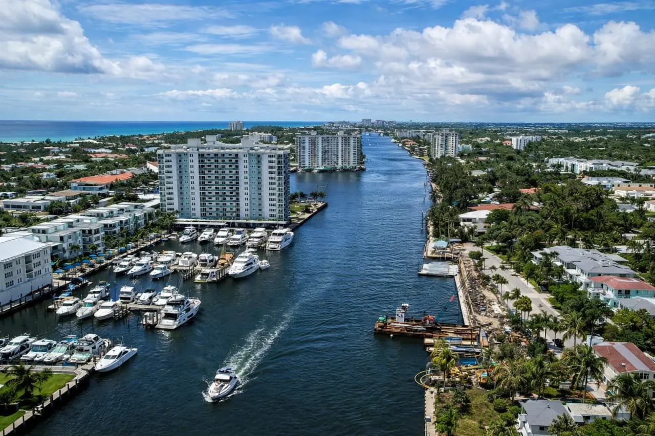 Aerial view of the Intracoastal Waterway in South Palm Beach County, Florida, with a marina of moored yachts, mid-rise condominium buildings and waterfront homes along both banks.